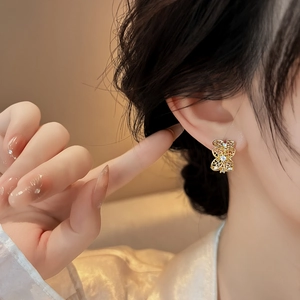 Primer plano de pendientes de flores caladas doradas con elegantes detalles de circonita.