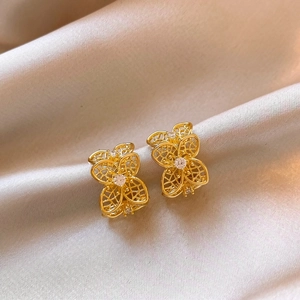 Detalle de pendientes de flores huecas bañados en oro con centros de circonitas