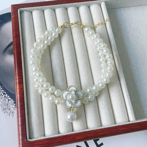 Close-up of double-layer pearl pet collar with white camellia pendant and gold clasp