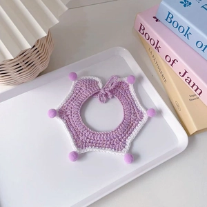 Detail of handmade purple star-shaped pet scarf with soft pom-poms and golden silk texture
