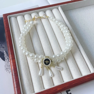 Detail of double-layer pearl pet necklace featuring a gold bee charm and teardrop pendants