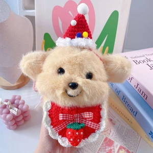 Close-up of plush bear with red knitted Christmas hat and strawberry crochet bib