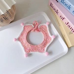 Detailed view of hand-knitted pink and white star-shaped pet collar with small pom-poms