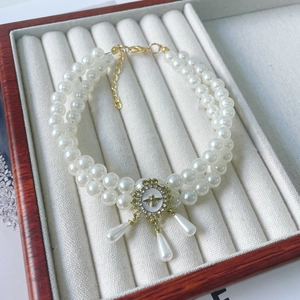 Close-up of double-layer pearl pet collar with golden bee pendant and rhinestone detail
