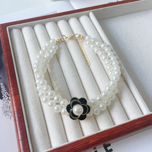 Macro detail of elegant double-row pearl pet necklace with camellia flower and gold lobster clasp
