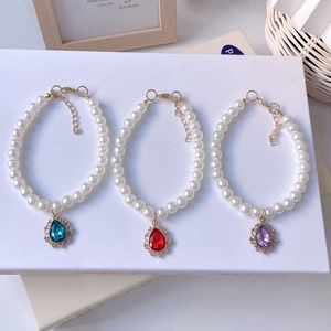 Detailed macro view of pear-shaped crystal pendants on elegant pearl pet necklaces