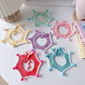 Close-up of handmade crochet star pet scarves with colorful pom poms and braided ties