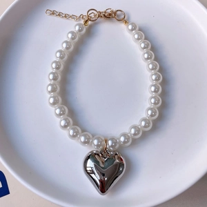 Macro detail of French vintage pet necklace with white pearls and silver heart pendant