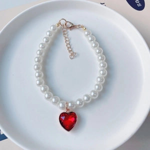 Détail d'un collier de perles pour animaux avec pendentif cœur rouge et fermoir doré