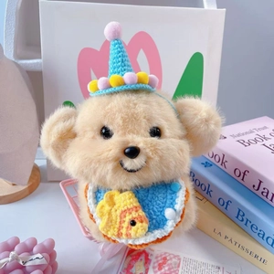 Detail of plush bear with blue crochet birthday hat and small fish pattern bib