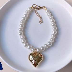 Detailed macro view of white pearls with a golden heart pendant and lobster clasp