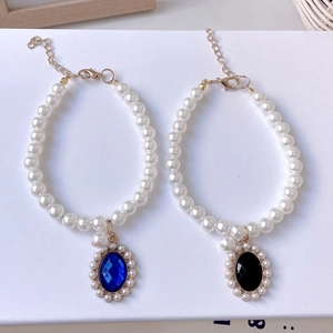 Detalle del collar de perlas para mascotas con colgantes de gemas azules y negras