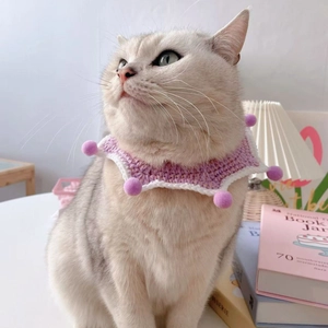 Detailed view of handmade pink crochet cat scarf with soft plush balls on a pet model
