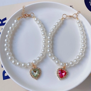 Detail view of colorful heart crystal pendants on pearl pet necklaces with gold clasps