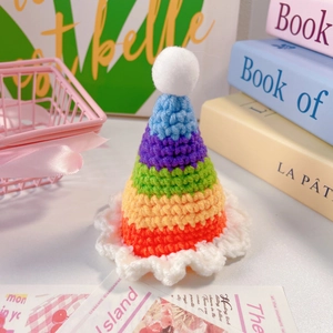 Détail d'un mini chapeau arc-en-ciel au crochet pour animaux avec pompon blanc