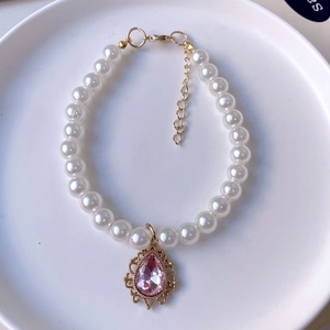 Detailed view of white faux pearl pet necklace with a pink teardrop crystal pendant