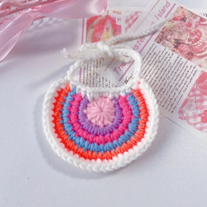 Détail d'un bavoir crocheté fait main pour animaux avec rayures arc-en-ciel et liens blancs