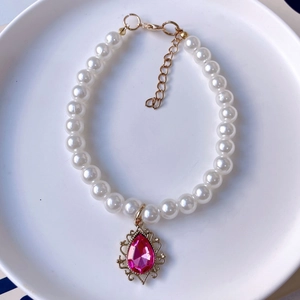 Detail of pet pearl necklace with pink teardrop gemstone pendant and gold lobster clasp