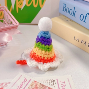 Détail d'un chapeau arc-en-ciel au crochet pour animaux avec pompon blanc et bords ondulés