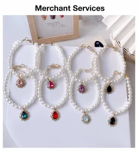 Close-up of pearl pet necklaces featuring vintage teardrop crystal pendants in various colors