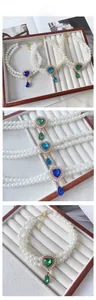 Detail showing double-layer pearl necklaces with blue and green heart-shaped crystal pendants