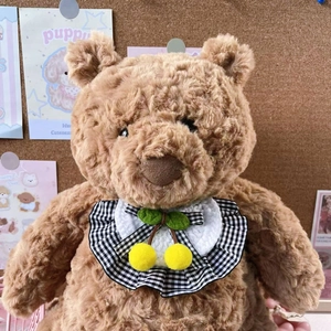 Detail of plush bear doll wearing a black and white checkered collar with cherry accents