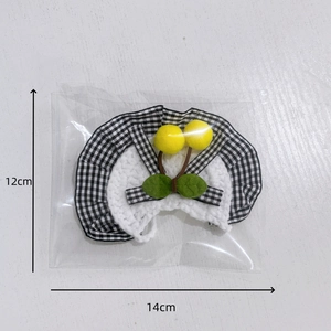 Detailed view of hand-woven cat bib with cherry pompoms and measurements shown