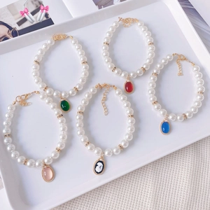 Close-up of five colorful vintage pearl pet necklaces with oval gemstone pendants