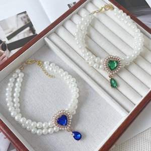Detail of double-layer pearl pet necklace with emerald and sapphire heart pendants