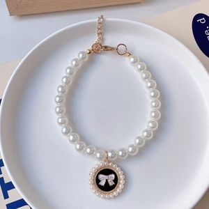 Detailed shot of pet pearl necklace with camellia bow pendant and gold lobster clasp