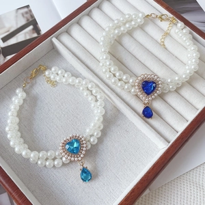 Detail of double-layer pearl pet necklaces with heart and teardrop gemstone pendants