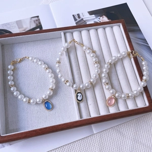 Detailed macro of three-piece vintage pearl pet collars with colorful cameo and gemstone charms