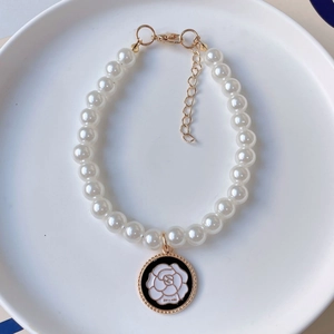 Detail of pet pearl necklace with black enamel camellia pendant and golden clasp