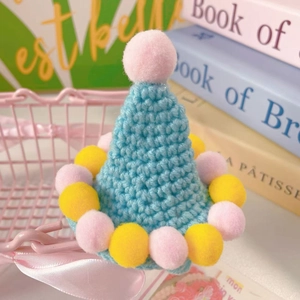 Detail of light blue handmade crochet pet hat with colorful pompoms and cute pointed top