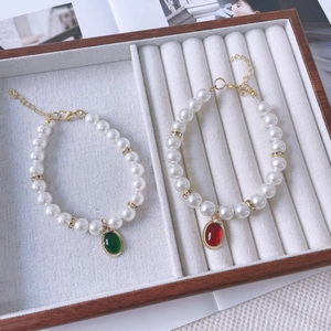 Detail of vintage pet pearl necklaces with emerald and ruby pendants in a wooden box