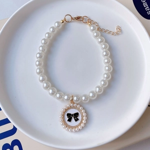 Detailed view of pearl pet necklace with golden lobster clasp and black bow pendant