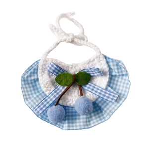 Handmade crochet pet bib with blue gingham frills and cherry decorations on white background