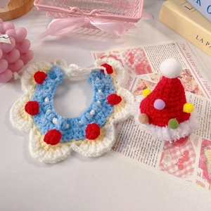 Handmade crochet pet set with a blue floral collar and a red pointed hat with pom-poms