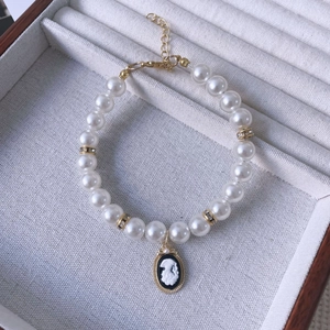 Close-up of vintage pet pearl necklace with a cameo pendant and gold diamond spacers