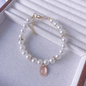 Close-up of pearl pet necklace with pink gemstone pendant and golden lobster clasp