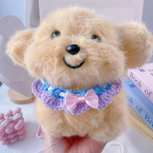 Close-up of plush puppy doll with blue and purple crochet bib and pink satin bow