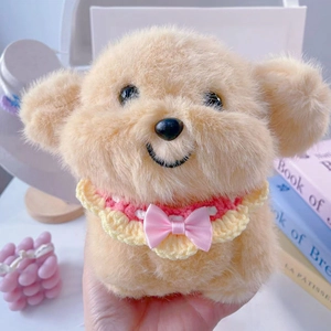Close-up of a plush dog toy wearing a pink and yellow hand-knitted bib with a satin bow