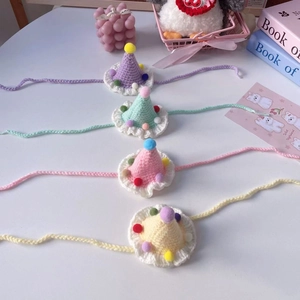 Detailed view of four colorful mini knitted pet party hats with soft pompom decorations