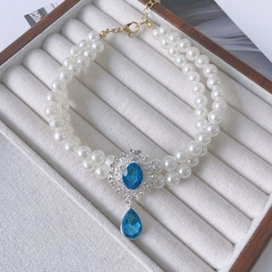 Close-up of double-layer pearl pet necklace with blue gemstone pendant and gold clasp