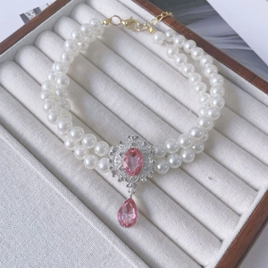 Close-up of double-layer pet pearl necklace with pink gemstone pendant on display