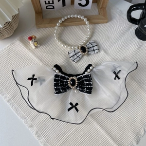 Detail view of pet lace collar and pearl necklace with tweed bow on white fabric