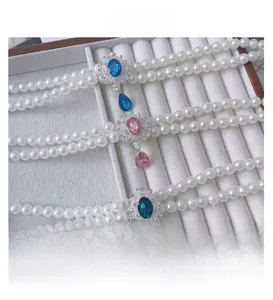 Close-up of handmade double-layer pearl pet necklaces with colorful gemstone pendants