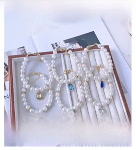 Detail of colorful crystal rectangle pendants on pearl necklaces for pets in a display box