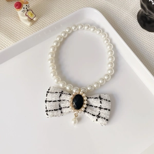 Detail showing pearl pet necklace with black white tweed bow and vintage jewel pendant