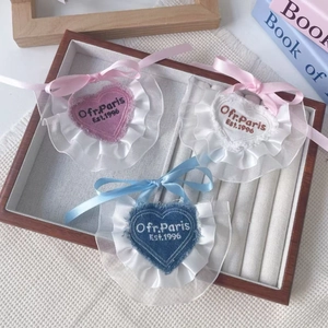 Detailed view of heart-shaped lace pet bibs in pink, white and blue with embroidery
